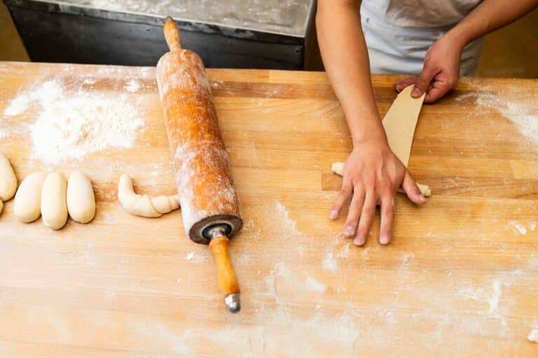 Croissant-Teig wird auf einer mehligen Arbeitsfläche ausgerollt.