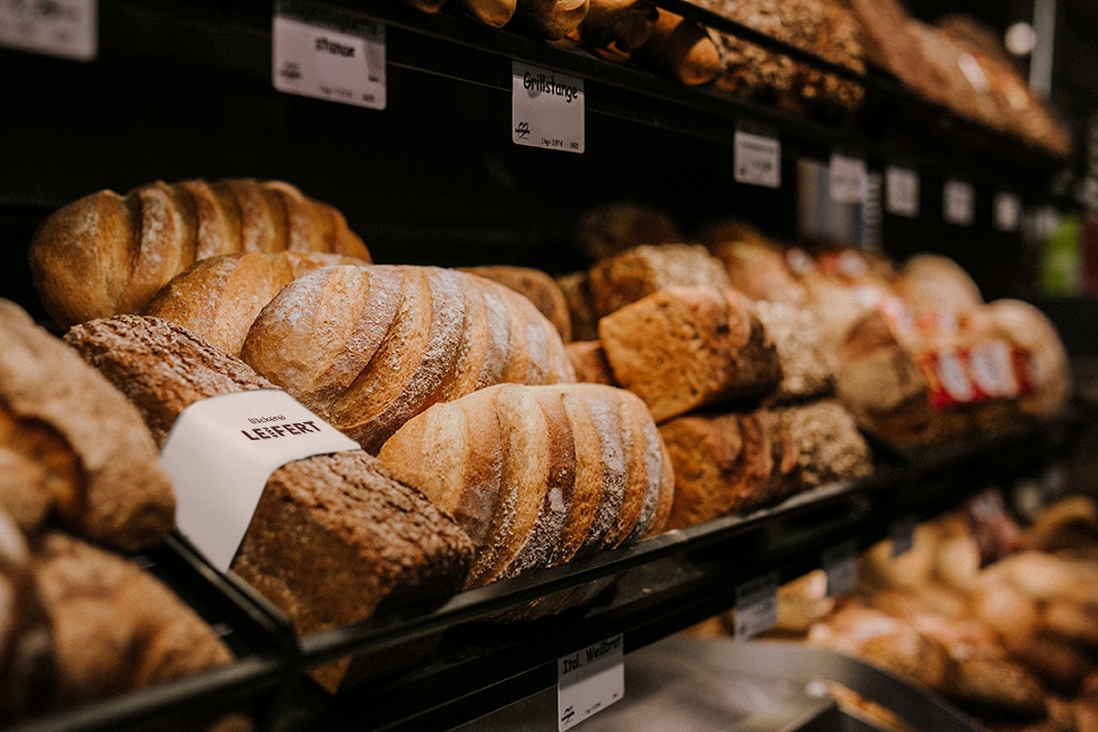 Frische Brote liegen in den Regalen der Bäckerei aus.