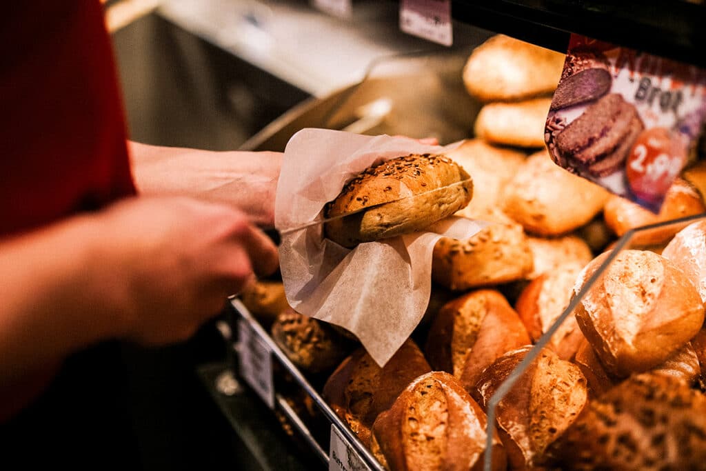 Eine Mitarbeiterin schneidet ein Brötchen auf.