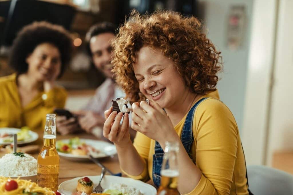 Eine Frau lacht beim Essen.